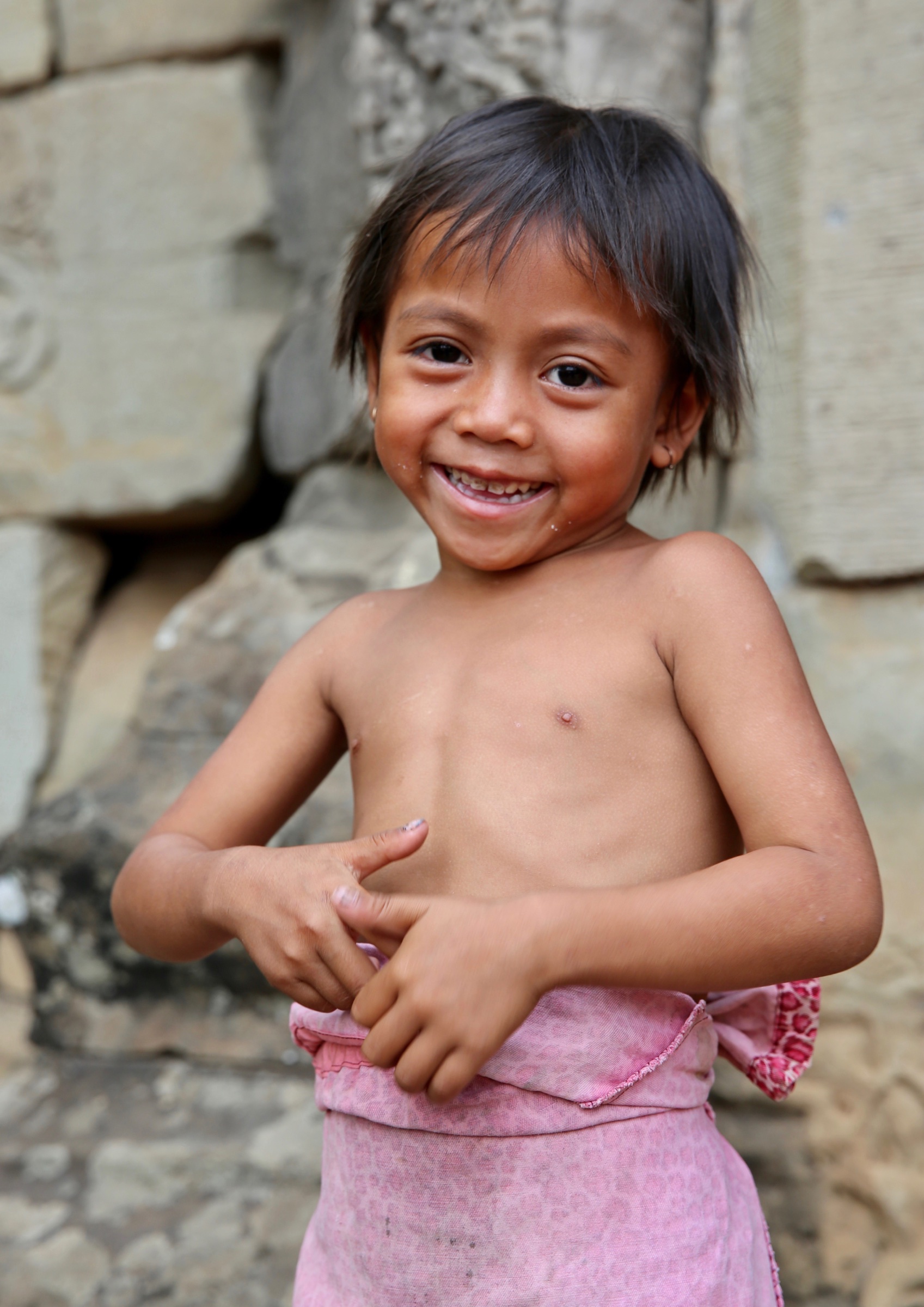 A smiling child standing near the temples of Cambodia