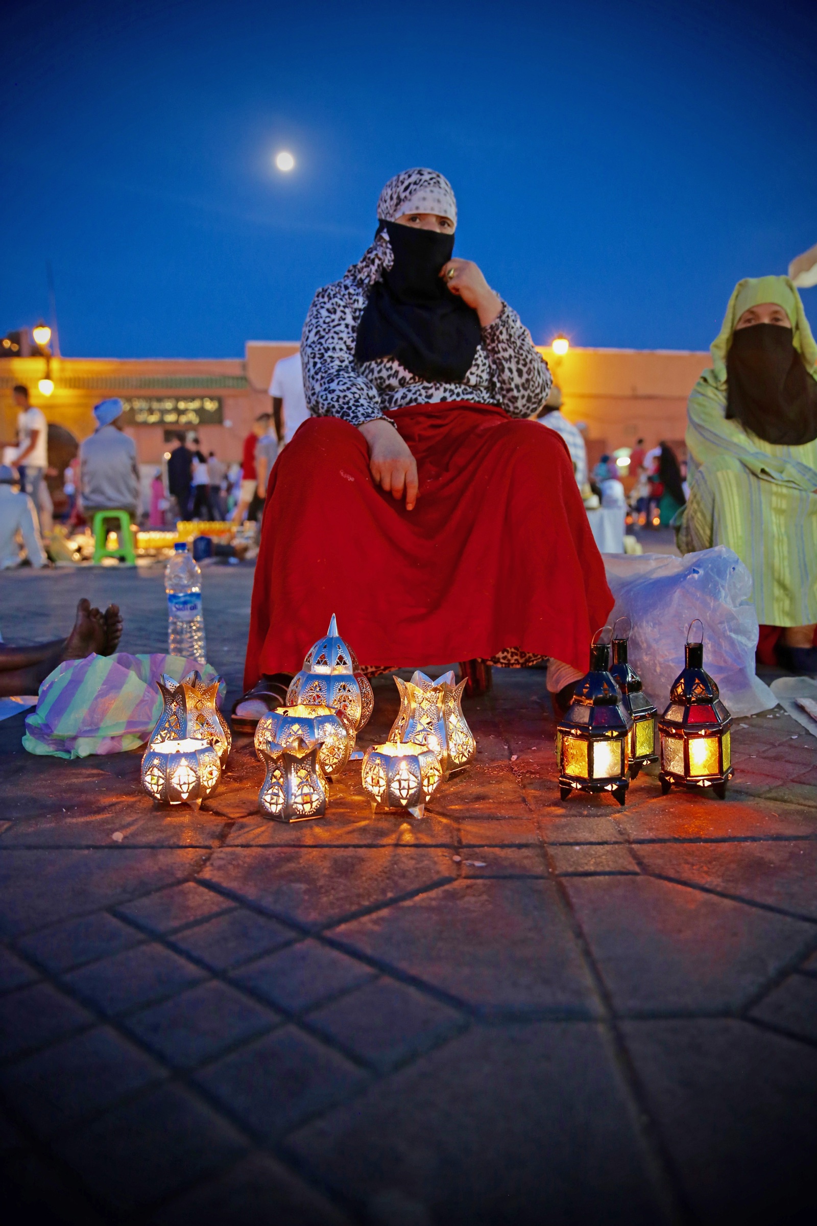 A lantern seller seated beneath a deep blue evening sky