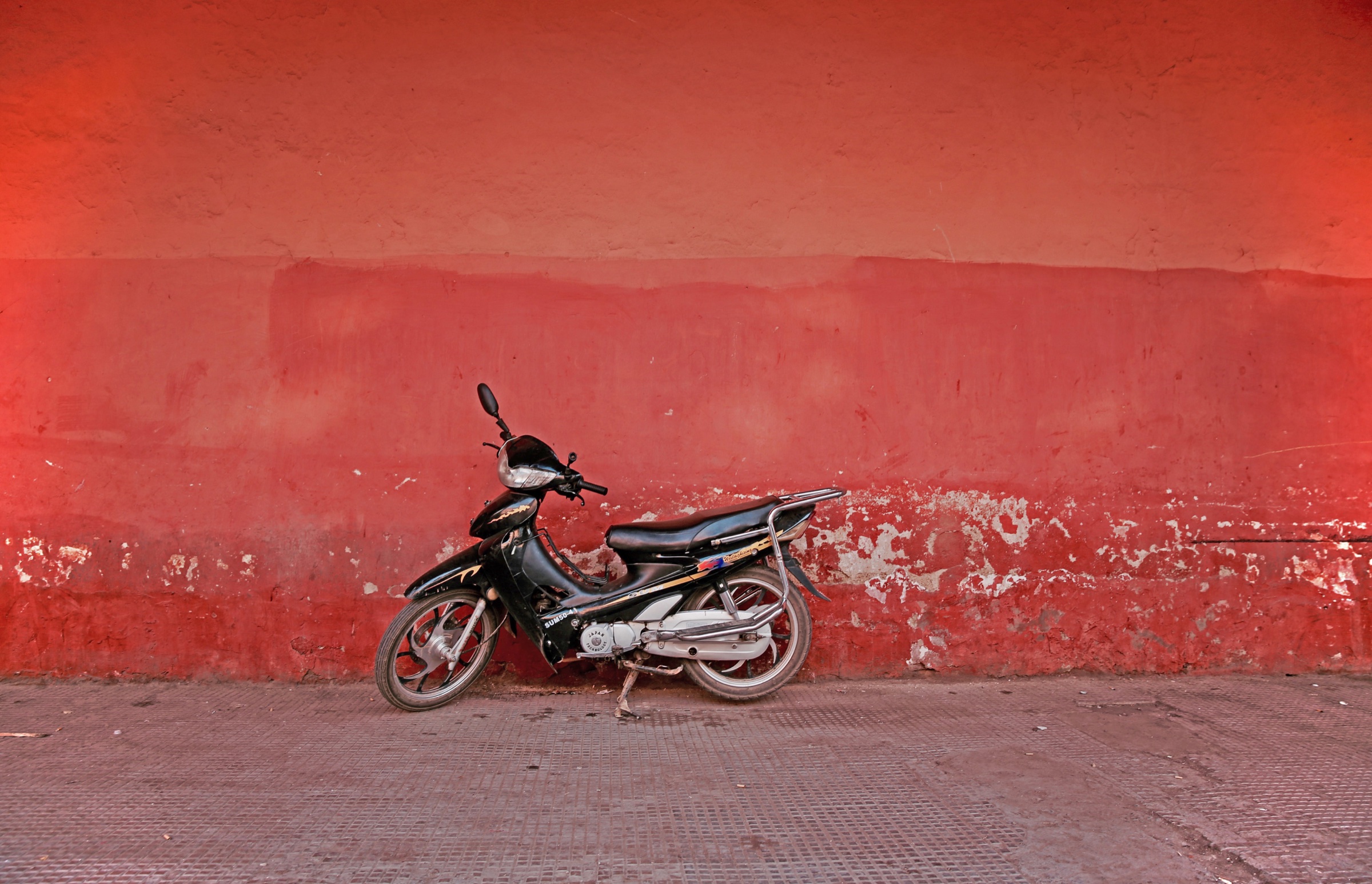 A motorcycle parked against a vivid red wall in Morocco