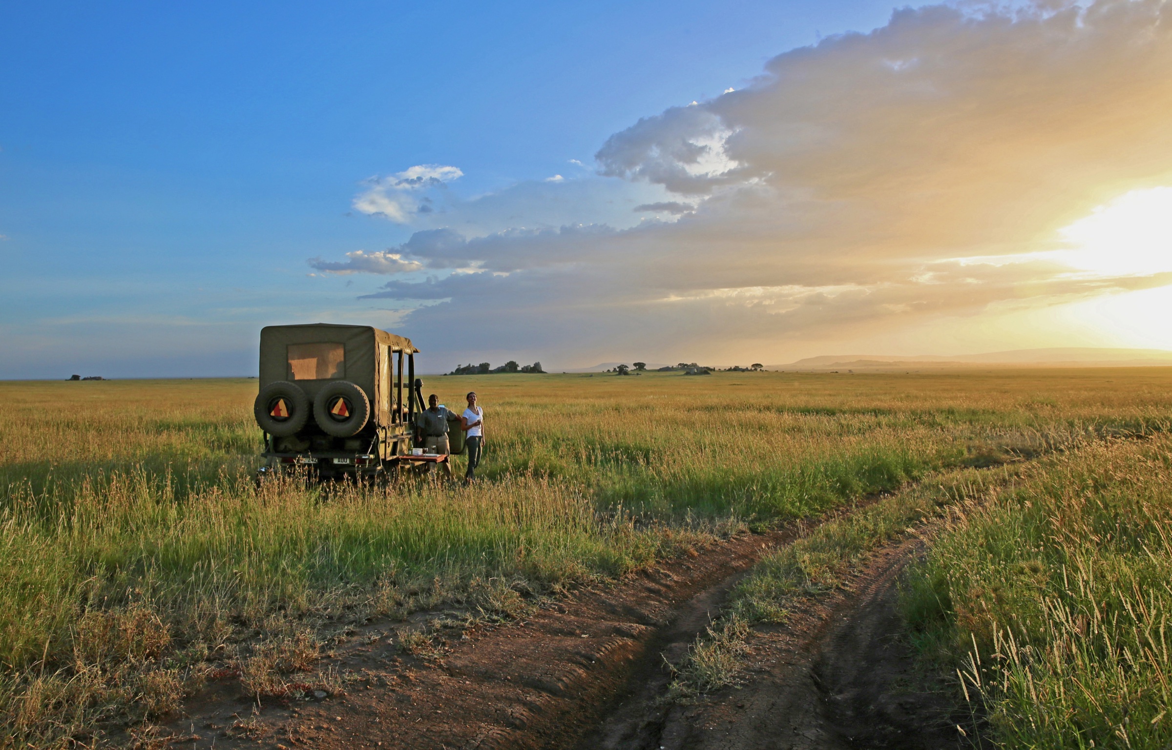 A safari vehicle at the edge of a golden Serengeti sunset