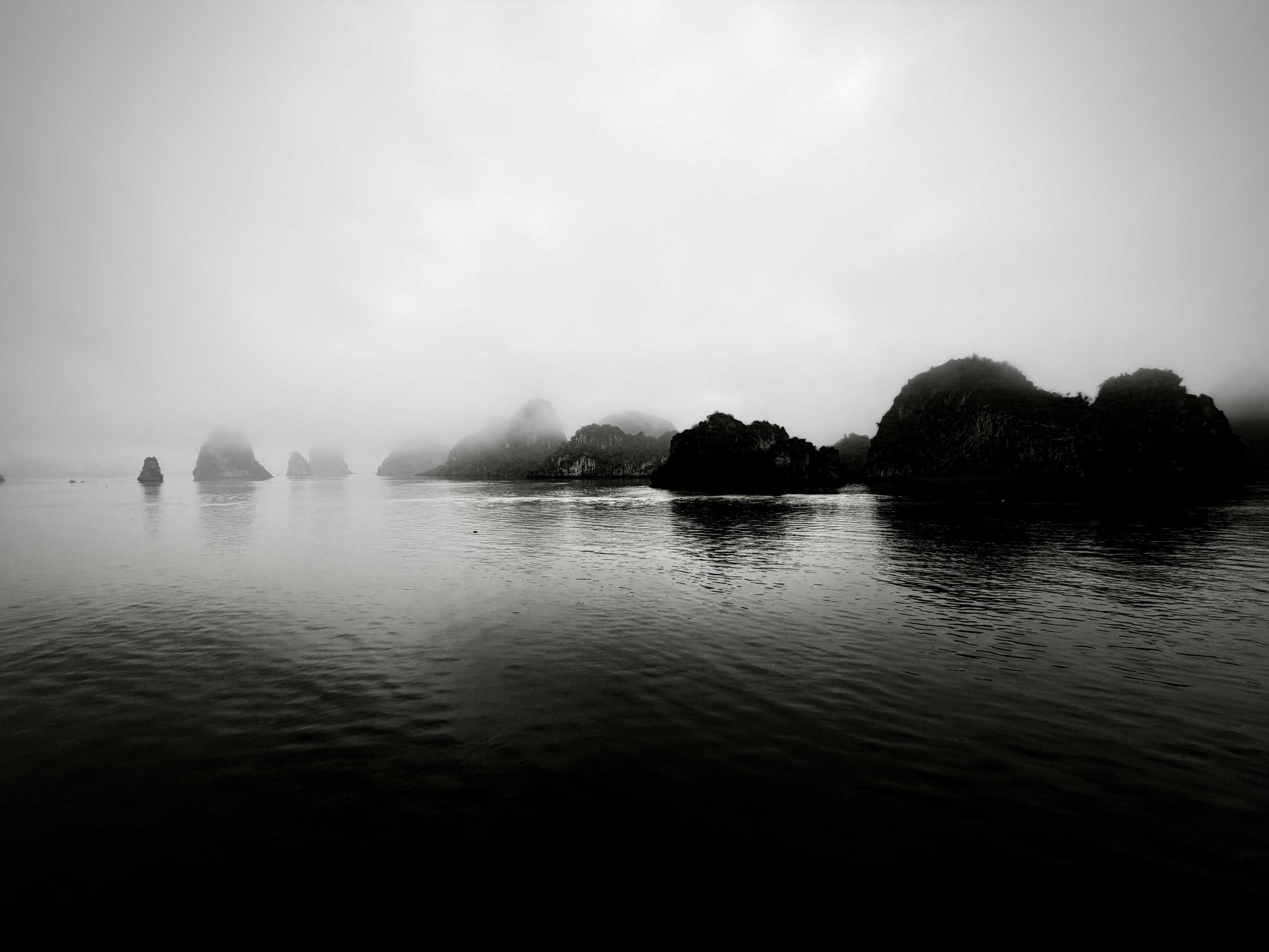 Misty rock formations reflected in the water at Ha Long Bay