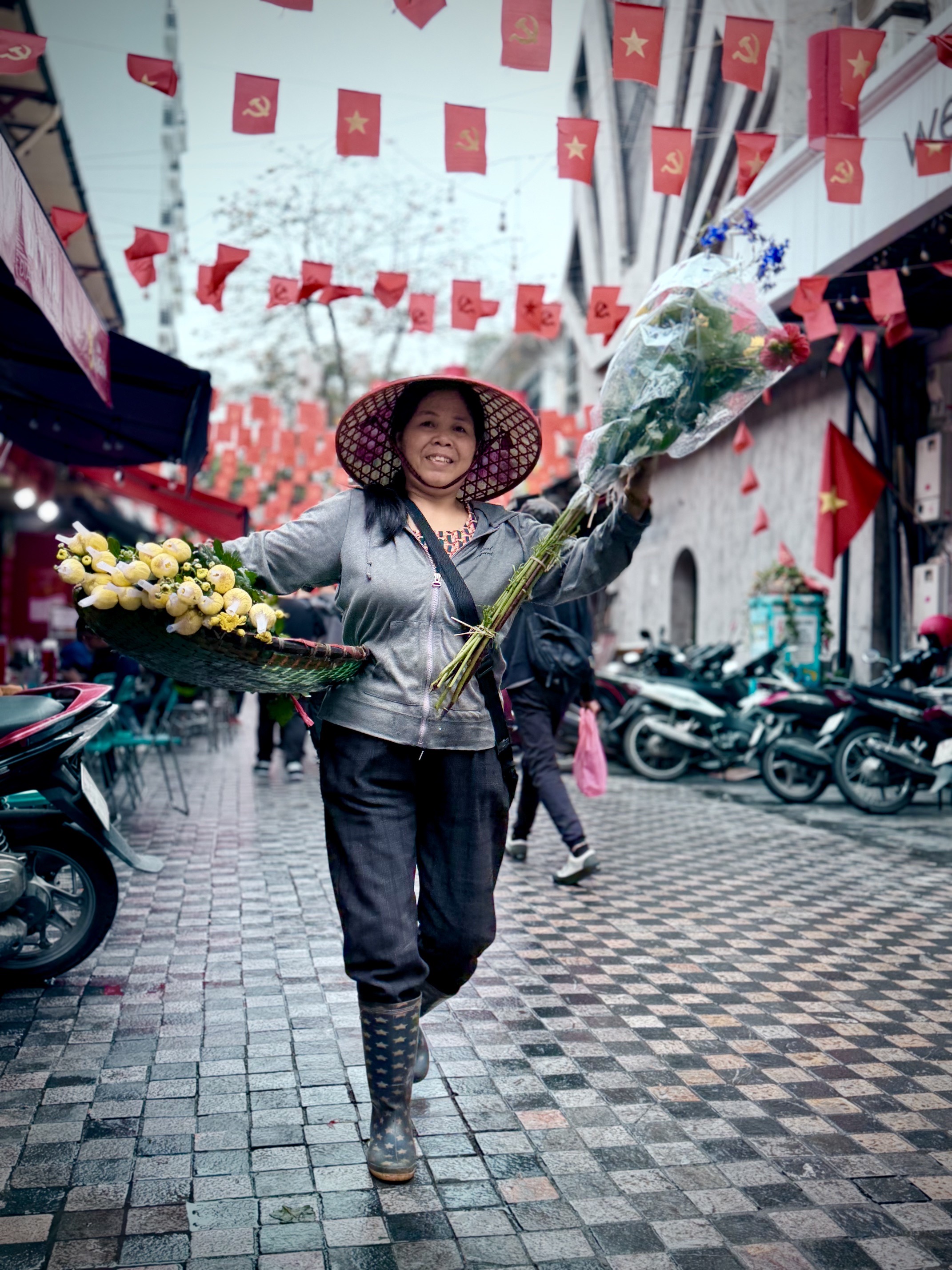A flower seller walking down a rainy street in Vietnam